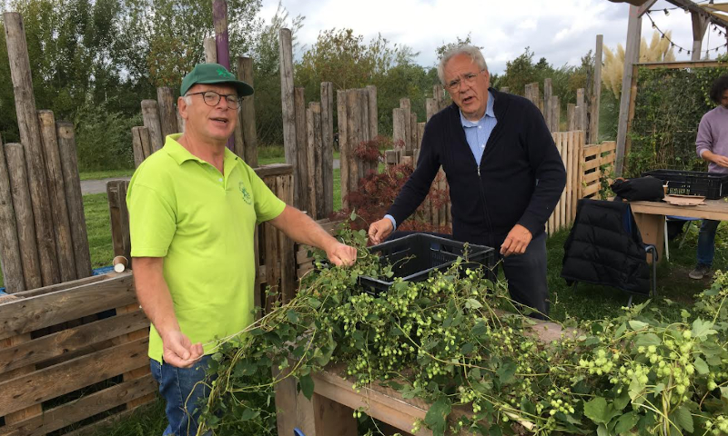 Twee mannen met een hoprank uit het Maximapark voor hen op tafel